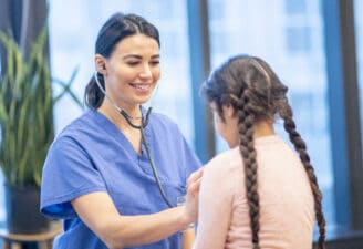 Nurse uses stethoscope to listen to a girl's heartbeat