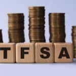 TFSA (Tax free savings account) acronym on wooden cubes on the background of stacks of coins