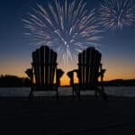 Canada Day fireworks over two Adirondack chairs on the wooden dock in Ontario, Canada