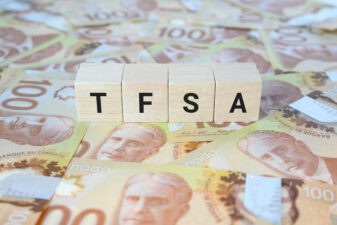 TFSA (Tax-Free Savings Account) on wooden blocks and Canadian one hundred dollar bills.