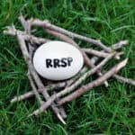 Close up of an egg in a nest of twigs on grass with RRSP written on it symbolizing a RRSP contribution.