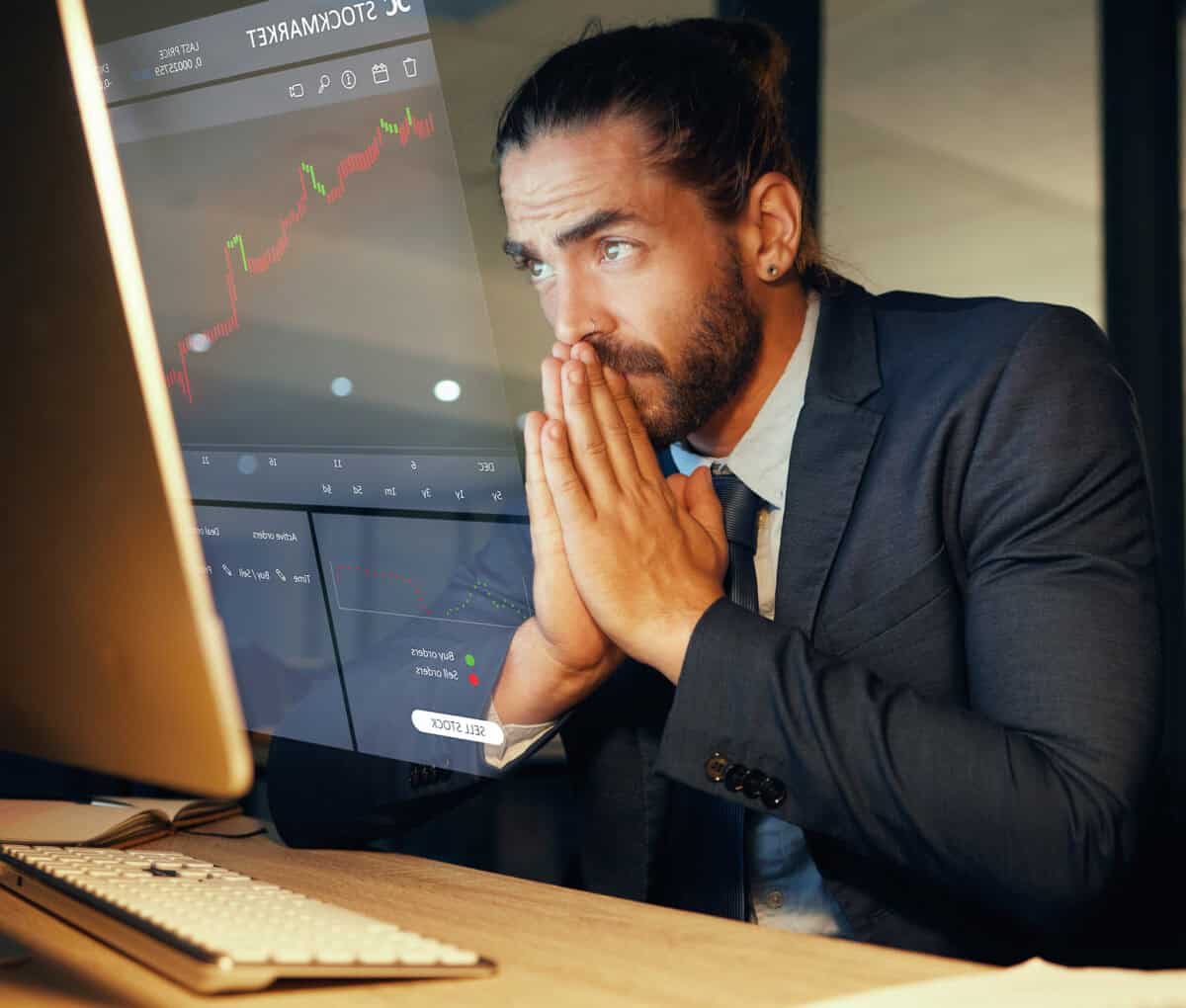 man in suit looks at a computer with an anxious expression