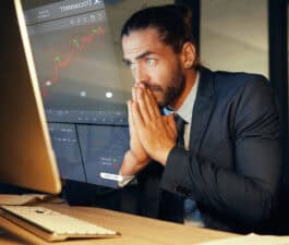 man in suit looks at a computer with an anxious expression