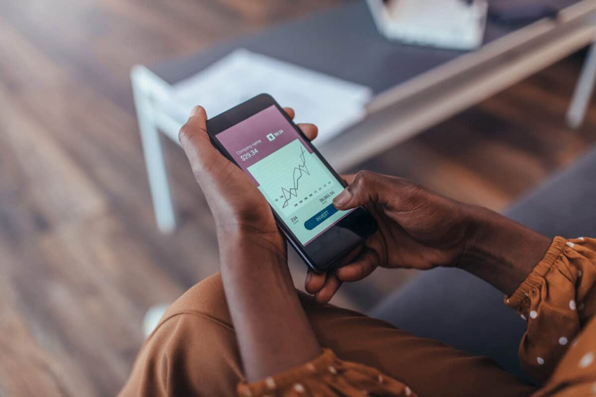 Person holding a smartphone with a stock chart on screen