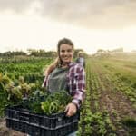 farmer holds box of leafy greens