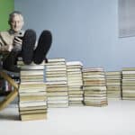 a man relaxes with his feet on a pile of books