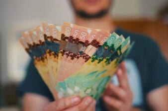 Man holds Canadian dollars in differing amounts