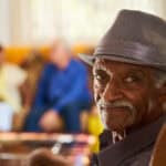 Man in fedora smiles into camera