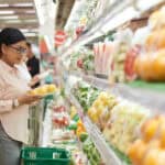 shopper chooses vegetables at grocery store