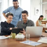 GettyImages-three smiling investors_using tablet